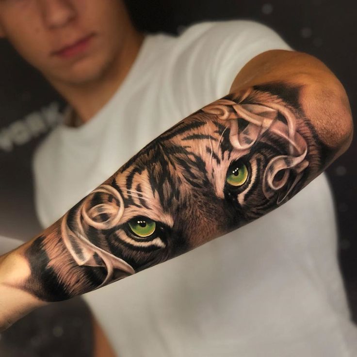 a man's arm with a tiger and green eyes tattoo on the upper half of his arm