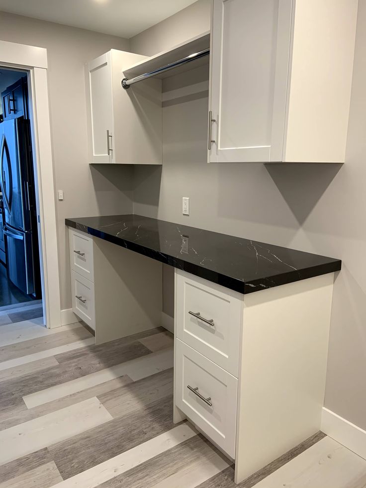 an empty kitchen with white cabinets and black counter tops in the middle of the room