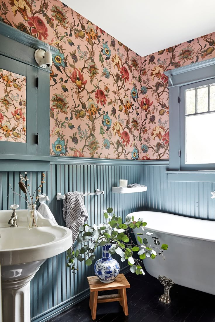 a bathroom with blue and pink wallpaper, a white bathtub and a sink