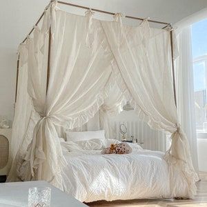 a bed with white sheets and curtains in a room