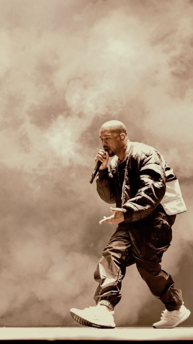 a man standing on top of a roof while holding a microphone in his right hand