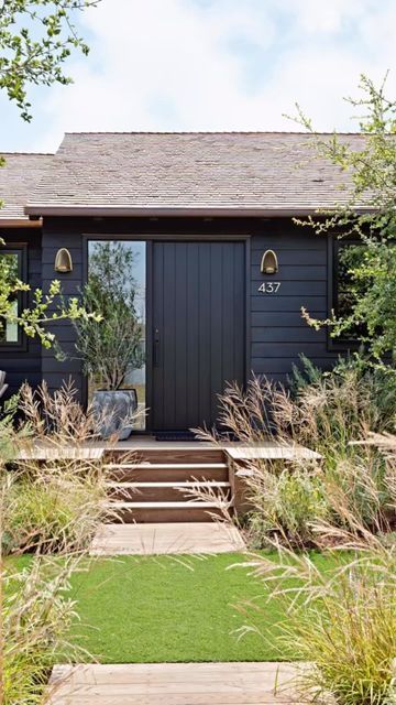 a black house with steps leading up to the front door and grass area around it