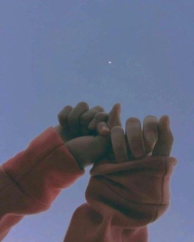 a person holding their hands up in the air with a kite flying overhead behind them