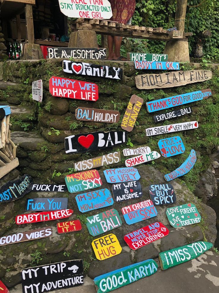 many different signs are posted on the side of a rock wall in front of a house