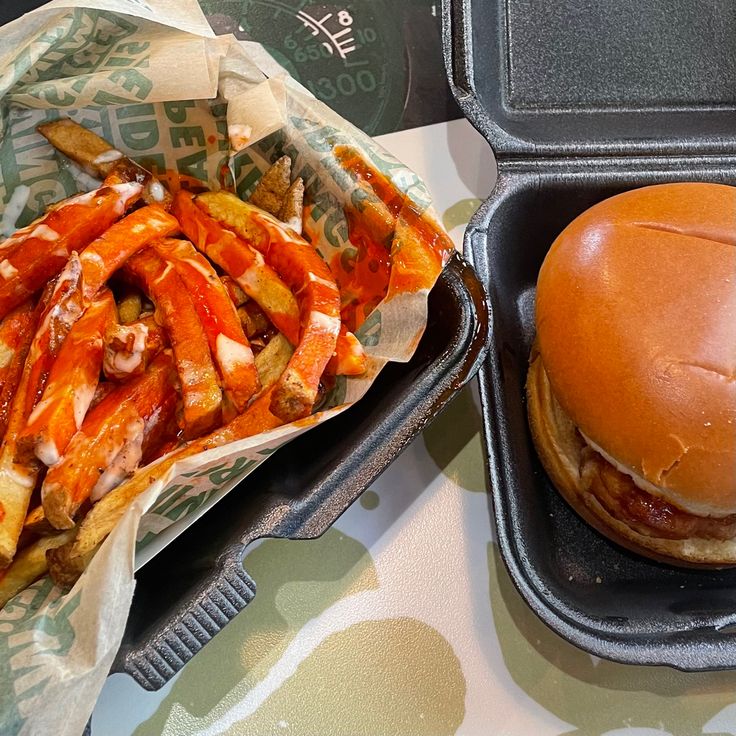 a sandwich and french fries are sitting on a table next to a container of sauce