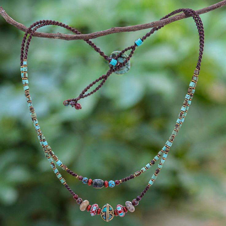 a necklace with beads and stones hanging from a tree branch