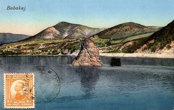 an old postcard shows a lake and mountains in the background, with a stamp on it