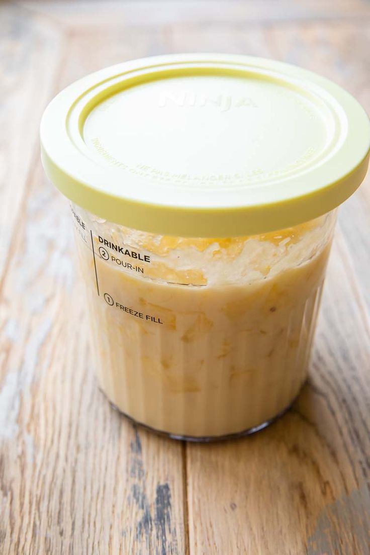 a glass jar filled with food sitting on top of a wooden table next to a yellow lid