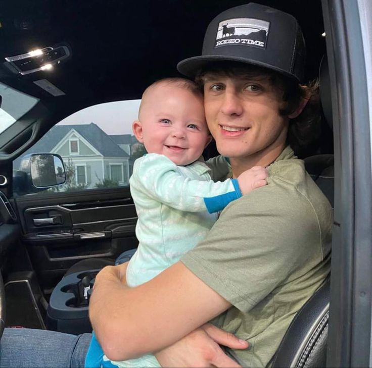 a man holding a small child in the back of a truck with his arms around him