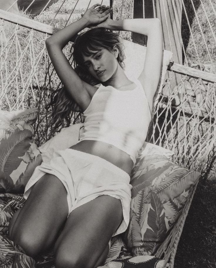 a black and white photo of a woman laying on a hammock