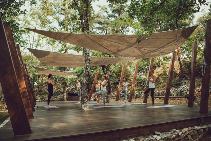 a group of people standing on top of a wooden platform in the woods doing yoga