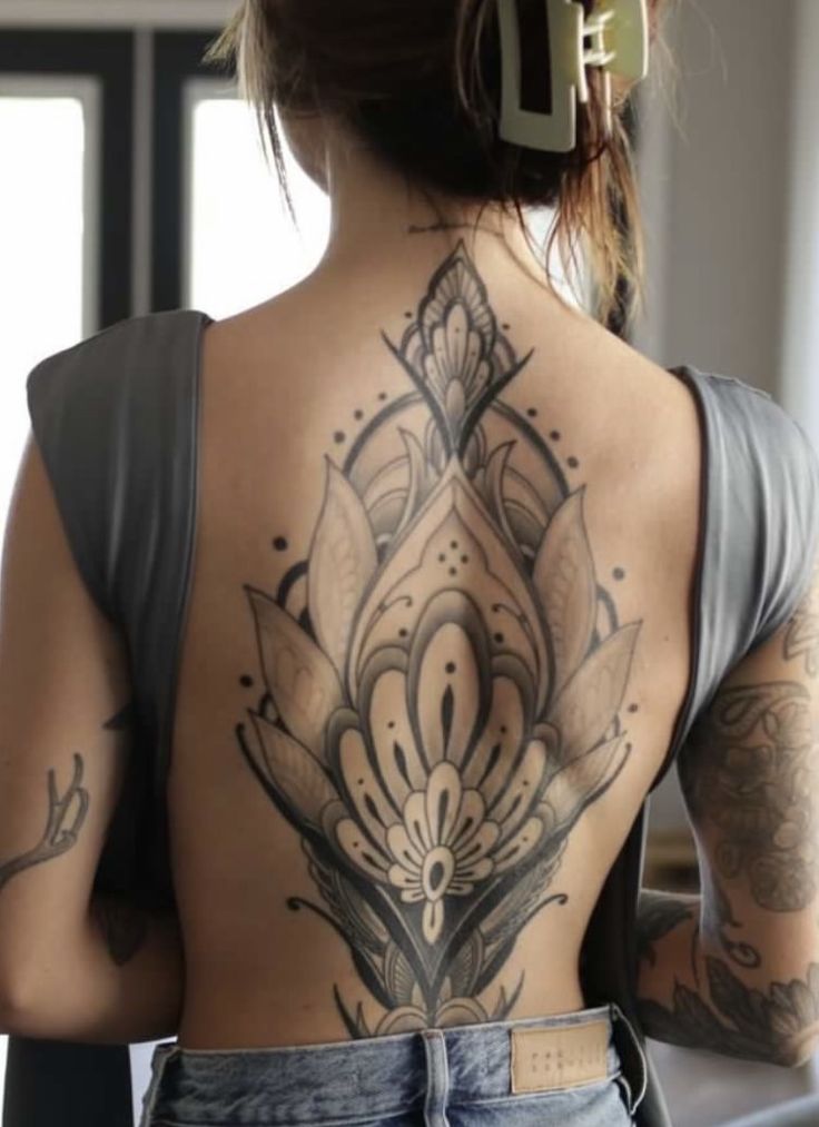 the back of a woman's body with tattoos on her upper and lower back