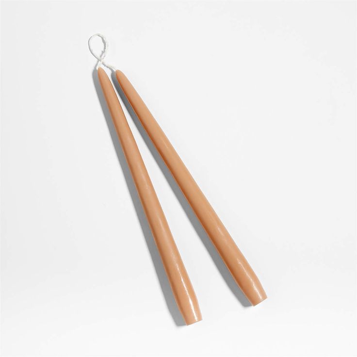 two wooden chopsticks sitting next to each other on a white surface with a string