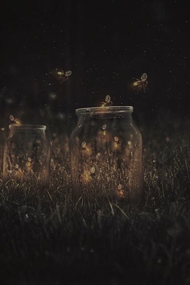 three glass jars with lights in them sitting on the grass, all lit up at night