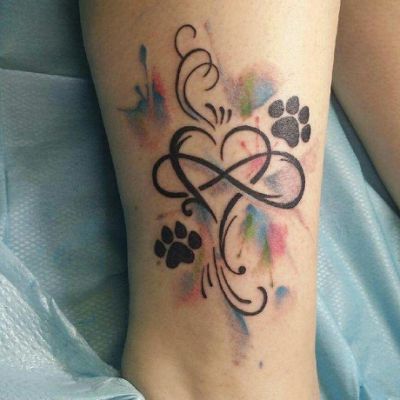 a tattoo on the leg of a woman with dog paw prints and an abstract heart