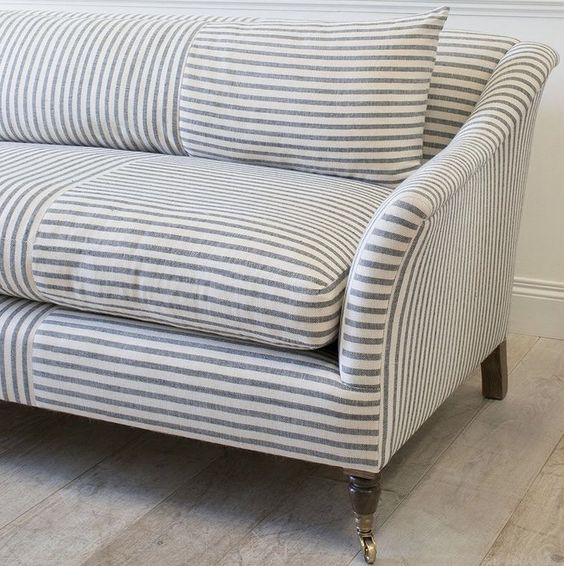 a striped couch sitting on top of a hard wood floor next to a white wall