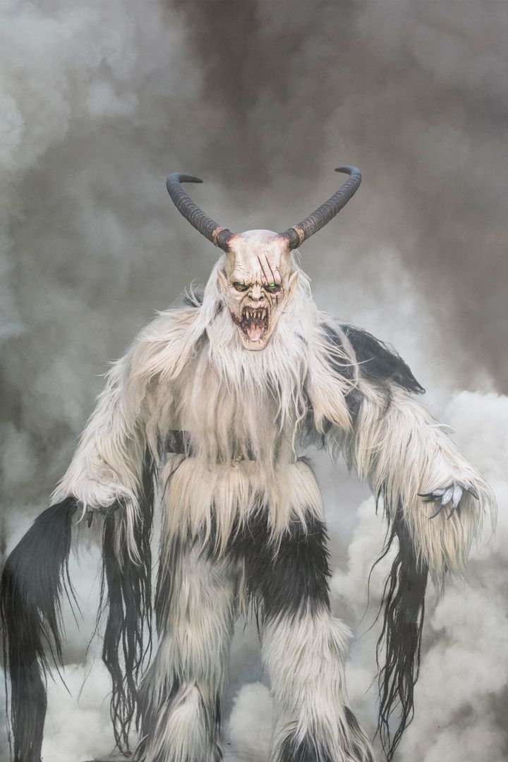 an illustration of a horned creature with long hair and large horns standing in the clouds