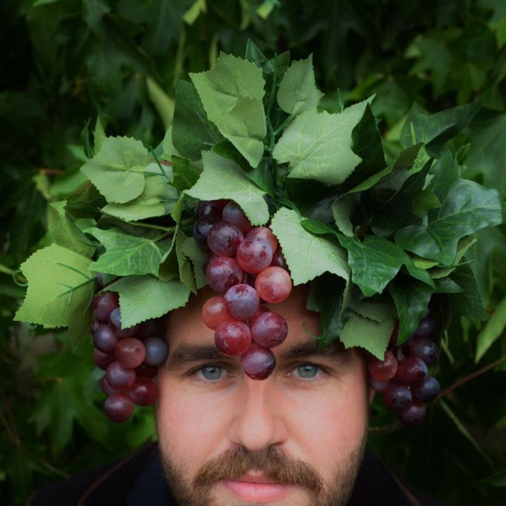 a man is wearing grapes on his head