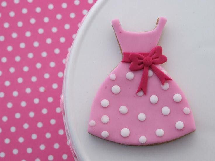 a cookie shaped like a dress on top of a white plate with pink polka dots