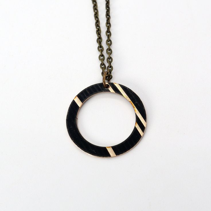 We might be biased, but circles are our favorite shape. This design is based around a snare drum rim / hoop, and makes for a simply yet meaningful design. Also, we're fans of circles and things coming full circle. Show your love for music with this reclaimed cymbal necklace. This piece is 1" in diameter. Looking for a smaller piece? Check out our Dark Hoop necklace which is 0.75" in diameter. - 18" Length Chain - choose from black or antique bronze (want a different length chain?     Just mention your desired length in the notes after adding this product to cart!) - 2" Chain extender included for length options - Cymbal piece is 1" x 1" - Reclaimed from broken cymbals made from bronze, painted black - Due to the reclaimed nature of the cymbals we use, each product is different. You may Hoop Necklace, Meaningful Design, Snare Drum, Chain Extenders, Upcycled Jewelry, Cymbals, Full Circle, Salt Lake City, Favorite Things Gift