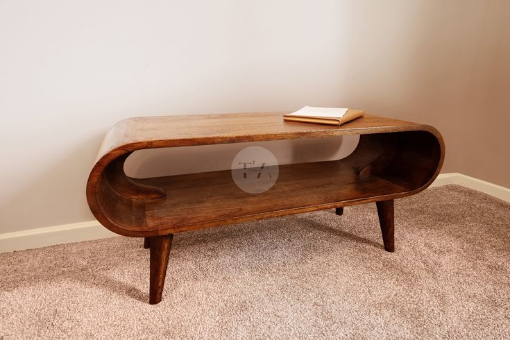 a wooden table with a book on top of it in a living room next to a wall