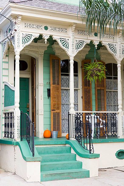 an old house with green steps and white trim on the front porch is decorated with orange pumpkins