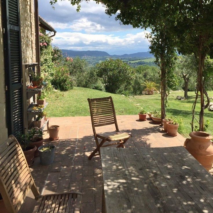 a wooden table sitting on top of a patio next to a lush green forest covered hillside