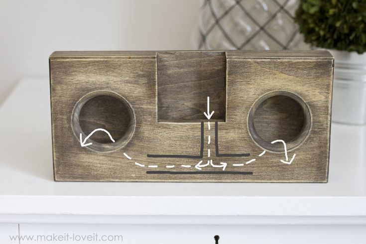 a wooden object with two holes in the middle on a white shelf next to a potted plant