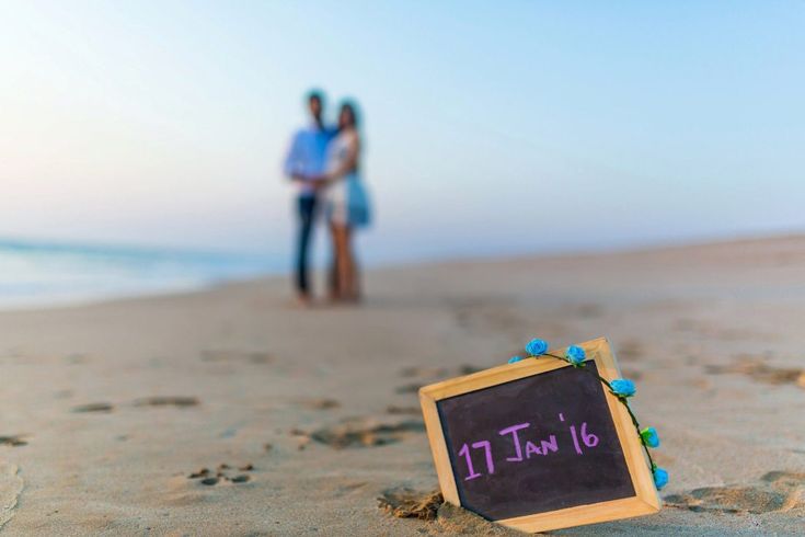 a sign that is on the sand with people in the background