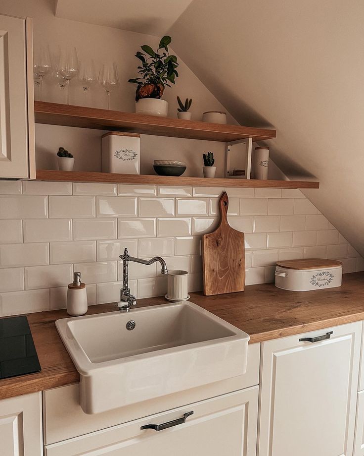 a white kitchen sink sitting under a window next to a wooden counter top with dishes and utensils on it