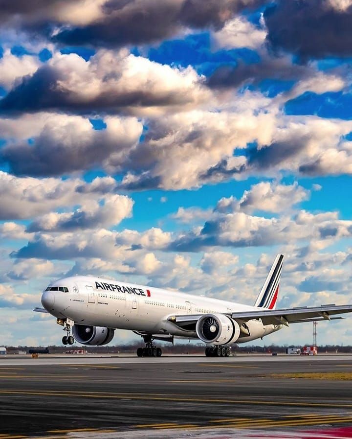 an airplane is sitting on the tarmac under cloudy skies and blue sky with white clouds