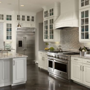 a large kitchen with white cabinets and stainless steel appliances in the center, along with marble counter tops