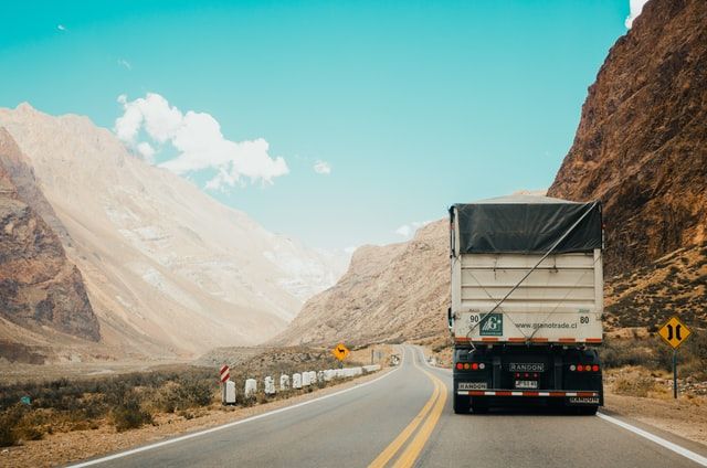 a truck driving down the road near mountains