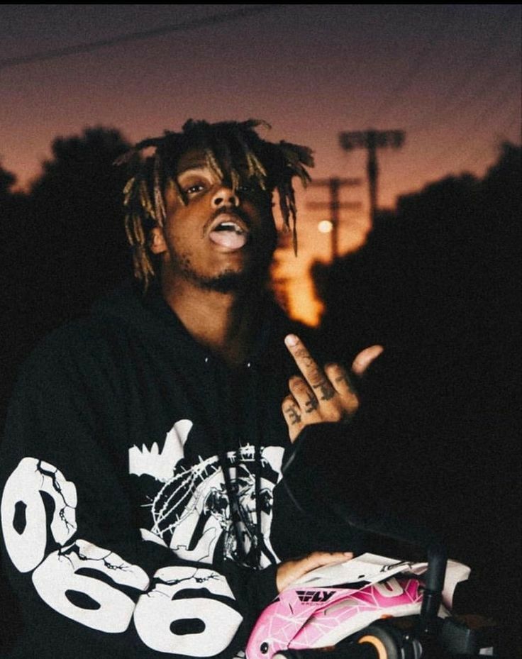 a young man with dreadlocks sitting on a pink skateboard in the dark