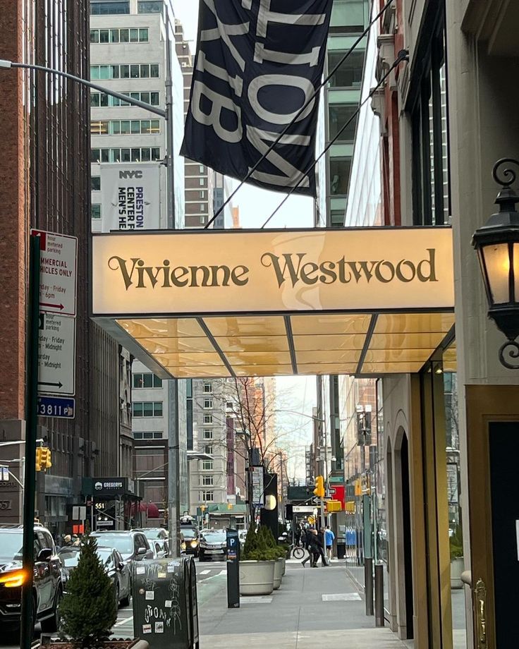 a street with cars parked on the side of it and a sign that says viviene westwood