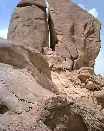 two large rocks sitting on top of a rocky hillside