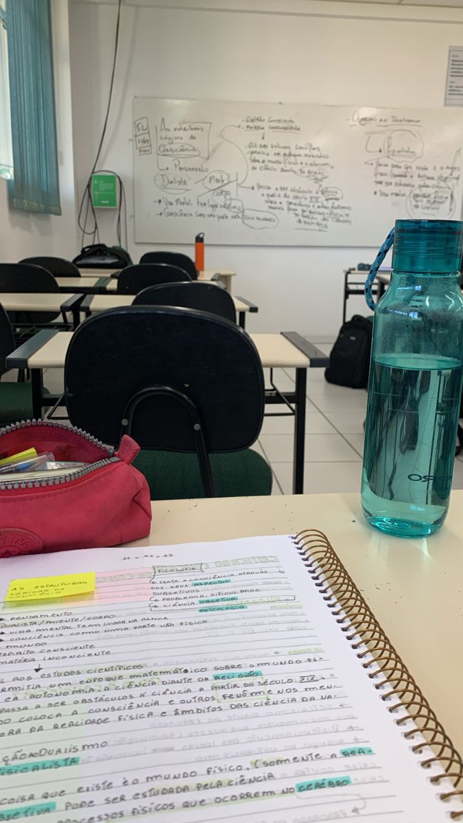 an open notebook sitting on top of a table next to a water bottle and pen