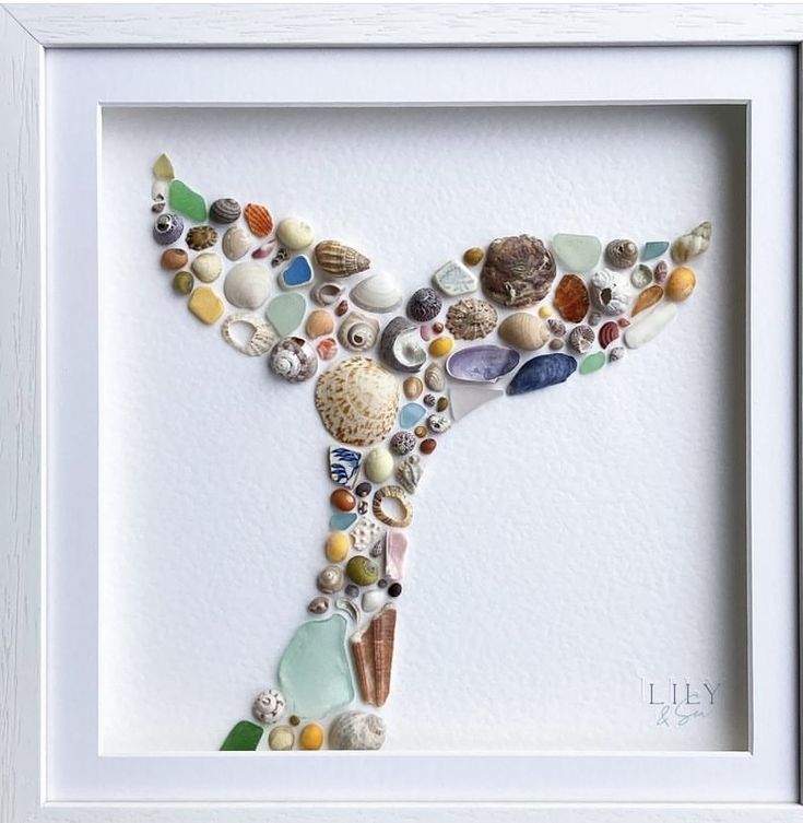 the letter y made out of seashells and sea glass is displayed in a white frame