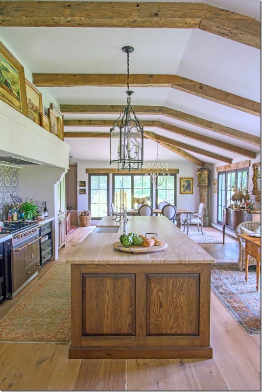 a large kitchen with an island in the middle and wood beams on the ceiling above it