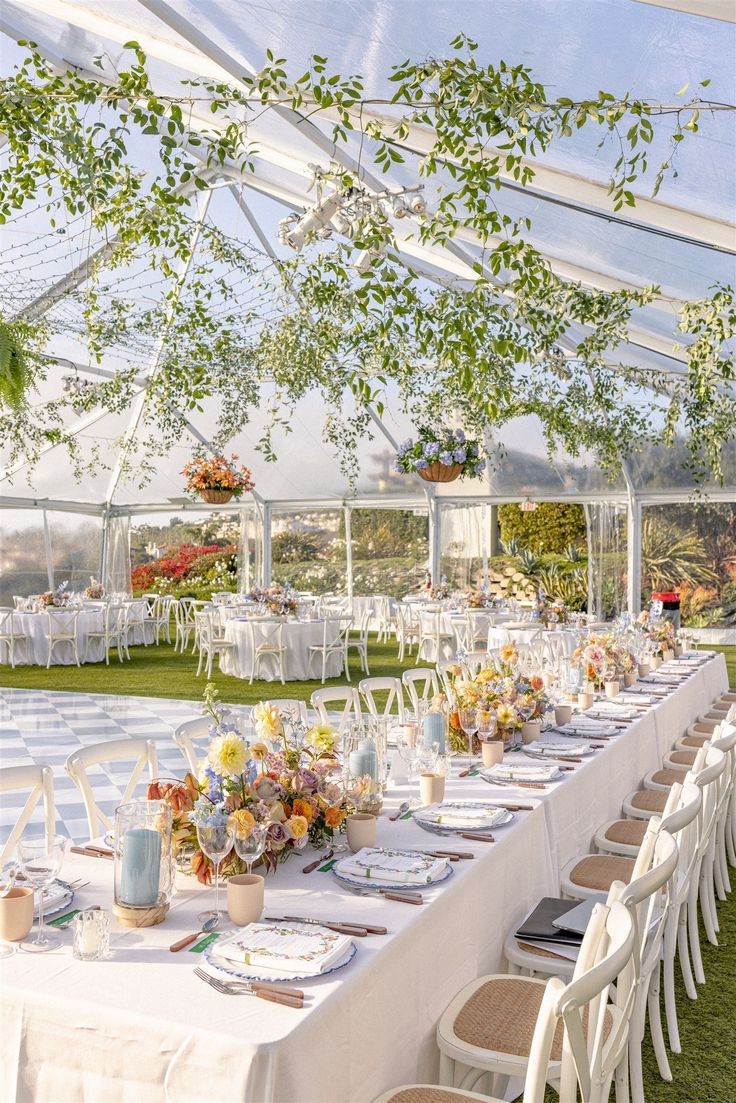 an outdoor dining area with tables and chairs set up for a formal dinner under a tent