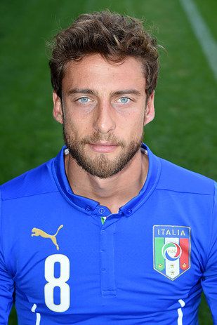 a man in a blue shirt posing for a photo on a soccer field with the italian flag