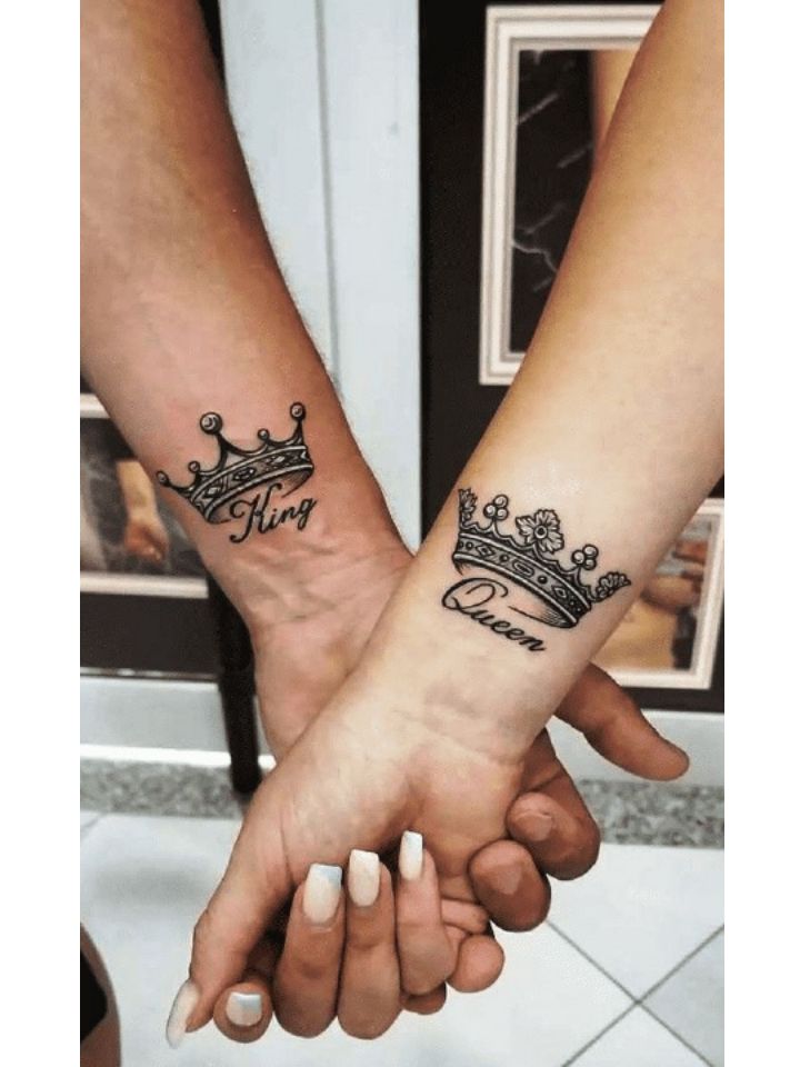 two people are holding hands with tattoos on their arms and one is wearing a crown