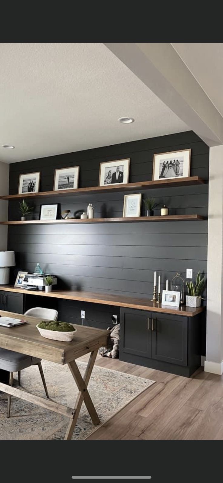 a living room filled with furniture next to a wall mounted bookshelf and shelves