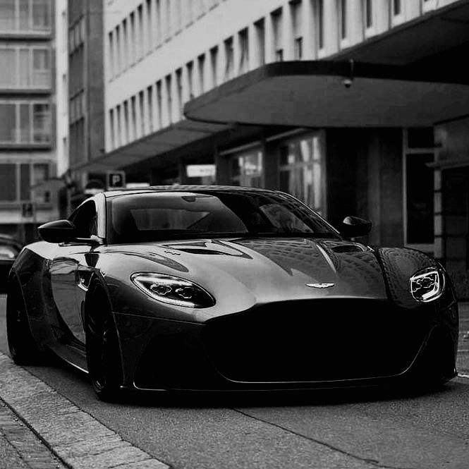 a black and white photo of a sports car parked on the side of the road