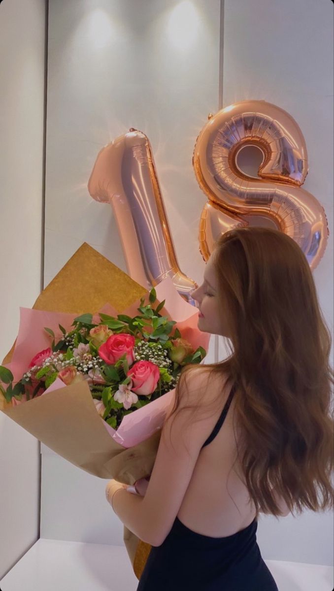 a woman holding a bouquet of flowers in front of the number six balloon and balloons