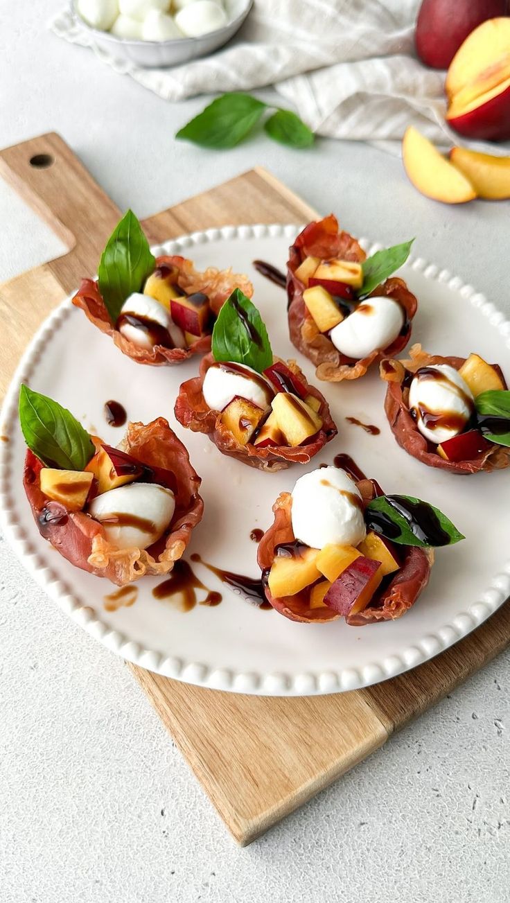 small appetizers on a white plate with green leaves and peaches in the background