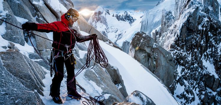 a man climbing up the side of a snow covered mountain