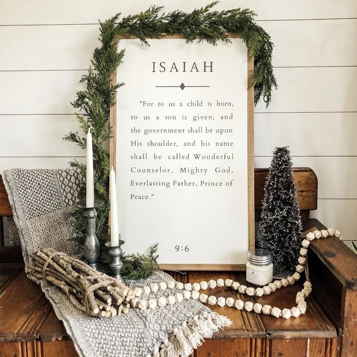 a wooden sign sitting on top of a table next to a candle and christmas decorations