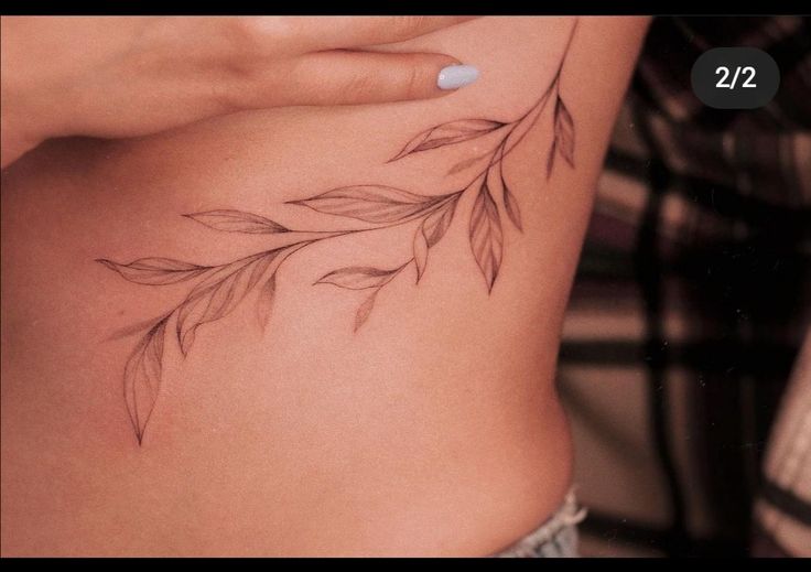 a woman's stomach with leaves tattoo on her side and the words 22 below it