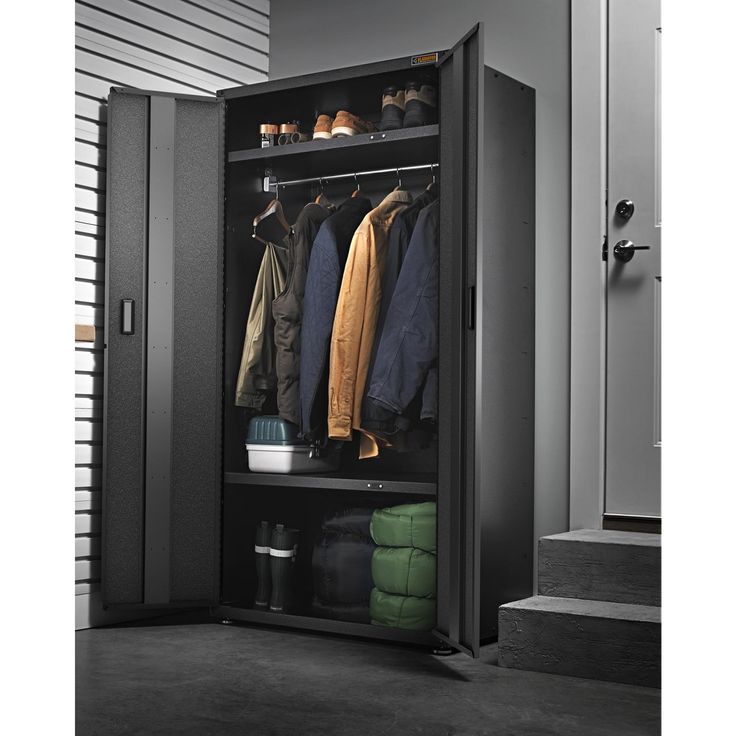 an open storage cabinet with clothes hanging on it